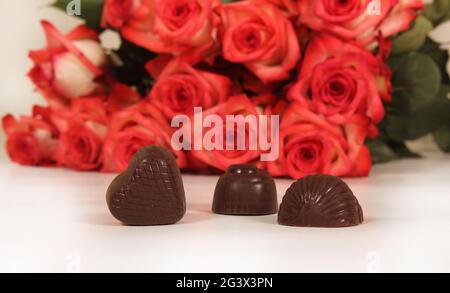 Bonbons au chocolat avec roses en arrière-plan, DOF peu profonde Focus sur le coeur chocolat Banque D'Images