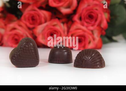 Bonbons au chocolat avec roses en arrière-plan, DOF peu profonde Focus sur le coeur chocolat Banque D'Images