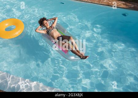 Femme de course mixte bronzer sur gonflable dans la piscine Banque D'Images