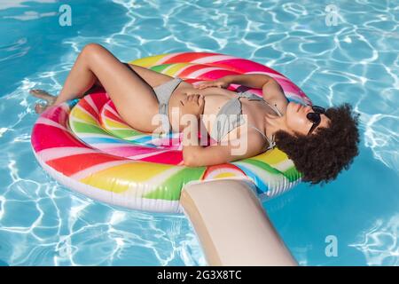 Femme de course mixte bronzer sur gonflable dans la piscine Banque D'Images