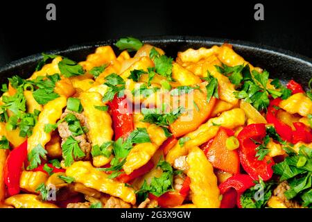 Pommes de terre frites avec légumes et champignons dans une casserole noire. Gros plan. Concept - nourriture grasse, problème d'obésité. Banque D'Images