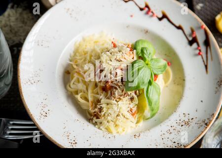 Pâtes italiennes au parmesan, sauce crémeuse et bacon. Spaghetti dans une assiette avec des herbes. Gros plan. Concept - nourriture, délica Banque D'Images
