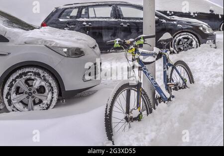 Hiver en ville – voitures et vélos garés et couverts de neige. Banque D'Images