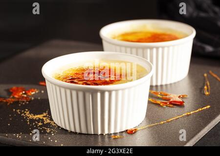 Crème brûlée - dessert traditionnel à la crème vanille française sur fond sombre. Banque D'Images