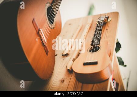 Ukulele: Gros plan d'un ukulele, prêt à jouer, accroché sur une étagère en bois Banque D'Images