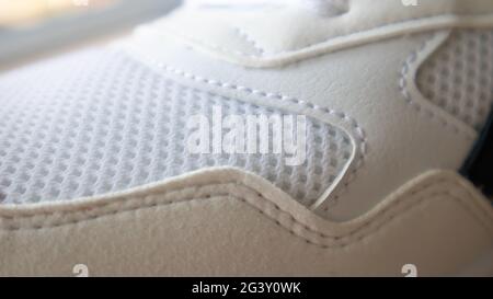 Tissu en mesh blanc sur une partie de chaussures de sport. Filet de patin de course. Treillis texturé SPORTSWEAR. Arrière-plan de texture textile. Détail d'une sneake blanche Banque D'Images