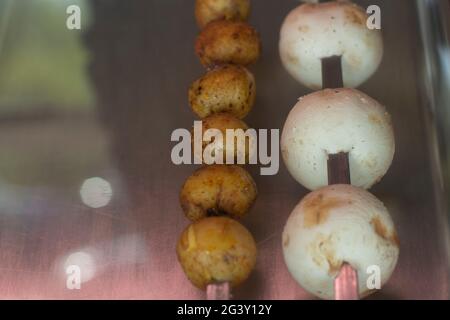Pommes de terre et champagnes sur brochettes. Champignons sur brochettes. Pommes de terre à couper sur la lame. Plats délicieux sur le comptoir. Banque D'Images