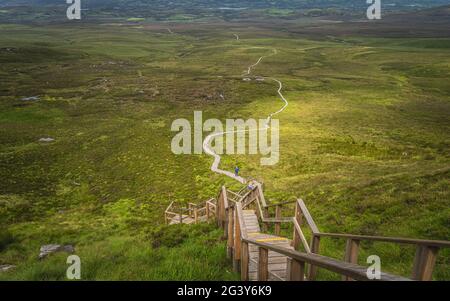 Les personnes grimpant sur les escaliers abrupts de la promenade en bois, pour atteindre le sommet de la montagne Cuilcagh Banque D'Images