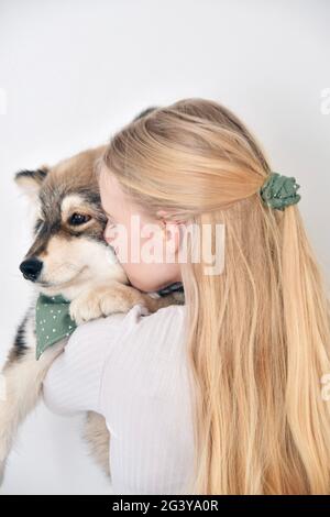 Photo d'une jeune femme embrassant un chiot chien de Lapphund finlandais et portant le bandana et le scrunchie assortis Banque D'Images