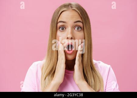 Gros plan d'une jeune étudiante choquée avec une peau bronzée et des cheveux justes qui lâchent la mâchoire en se touchant les joues avec étonnement Banque D'Images