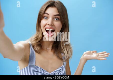 Prise de vue à la taille de charismatique optimiste enthousiaste mignonne blogger femme levant la main au-dessus de l'espace de copie et tenant l'appareil photo comme si recor Banque D'Images