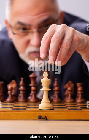 Un vieil employé de sexe masculin joue aux échecs sur le lieu de travail Banque D'Images