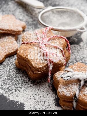 Biscuits cuits au pain d'épice en forme d'étoile saupoudrés de sucre en poudre une table noire Banque D'Images