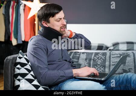 Homme fatigué tendu souffrant de douleurs au cou tout en travaillant à l'ordinateur. L'homme moque le cou, met sur le col, sitti Banque D'Images