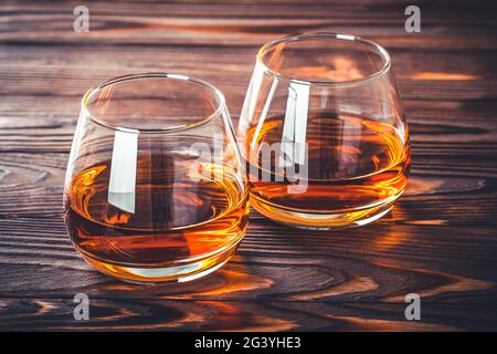 Deux verres de whisky, de cognac, de brandy sur une table en bois brun foncé. Bourbon. Gros plan sur la boisson alcoolisée forte. Rhum, scotch. Encore la vie dans un style rustique Banque D'Images