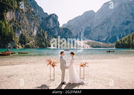 Le marié met un anneau à la mariée, au lieu de la cérémonie, avec une arche de colonnes de fleurs d'automne, sur fond de Banque D'Images