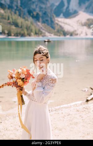 Belle mariée dans une robe blanche avec des manches et de la dentelle, avec un bouquet jaune d'automne de fleurs séchées et de roses pivoines, sur la la Banque D'Images