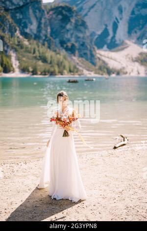 Belle mariée dans une robe blanche avec des manches et de la dentelle, avec un bouquet jaune d'automne de fleurs séchées et de roses pivoines, sur la la Banque D'Images