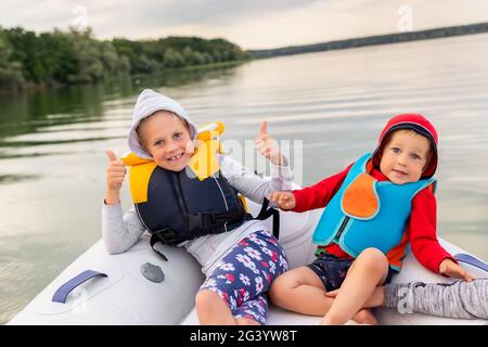 Deux adorables et adorables petits cacacasiens petit garçon et fille portant gilet de sauvetage avoir le plaisir d'équitation gonflable bateau à moteur sur la rivière ou le lac avec Banque D'Images