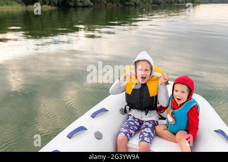 Deux adorables et adorables petits cacacasiens petit garçon et fille portant gilet de sauvetage avoir le plaisir d'équitation gonflable bateau à moteur sur la rivière ou le lac avec Banque D'Images