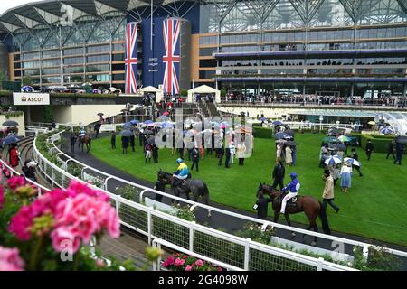 Les Racegoers se protègent sous des parasols tandis que les chevaux sont promenés autour de l'anneau de parade pendant le quatrième jour de Royal Ascot à l'hippodrome d'Ascot. Date de la photo: Vendredi 18 juin 2021. Banque D'Images