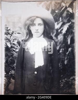 photographie vintage authentique de 1910 d'une jeune femme portant un chapeau debout dans le jardin. Concept d'individualité, nostalgie, début du XXe siècle Banque D'Images