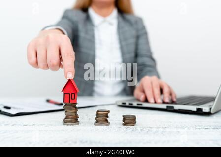 Tenir et pointer vers le modèle de maison. Une jeune femme qui tient la maison Banque D'Images