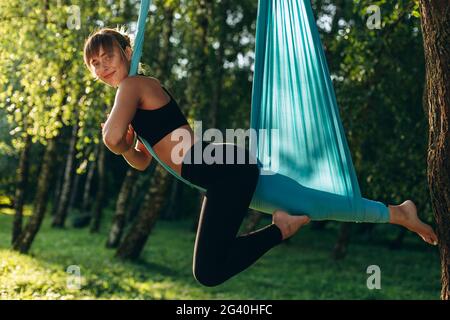 Belle fille faisant voler yoga dans le parc à l'extérieur . Je regarde avec plaisir la caméra Banque D'Images