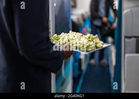 Des agents de bord avec plateau de fleurs de tiare de Tahiti fraîches saluent les passagers à bord de l'avion Air Tahiti Nui Boeing 787 Dreamliner, Paris Charles Banque D'Images