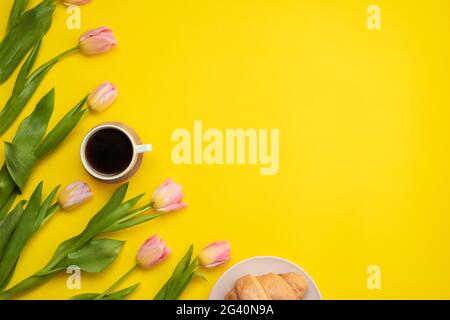 Magnifique tulipes roses, café et croissants sur fond jaune. Placer pour le texte. Concept de fête des mères. Banque D'Images