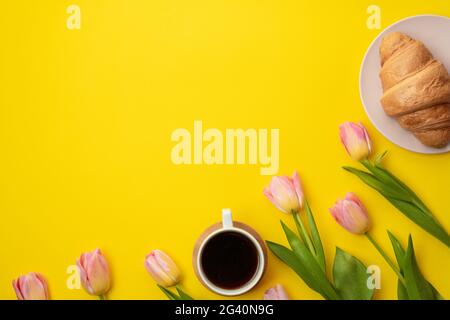 Magnifique tulipes roses, café et croissants sur fond jaune. Placer pour le texte. Concept de fête des mères. Banque D'Images