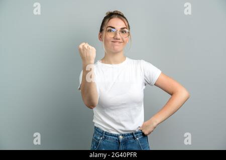 Une jeune jeune femme en colère montre un poing à l'appareil photo, menace quelqu'un, agite avec énerver sa lèvre inférieure, froissée son nez, habillé en cl décontracté Banque D'Images