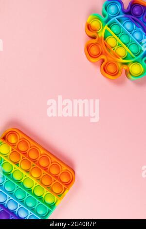 Les jouets anti-stress le pop, simple bosselé, sur fond rose, espace de copie. Concept de divertissement à la mode pour les enfants de violon, jouets sensoriels pour le développement Banque D'Images