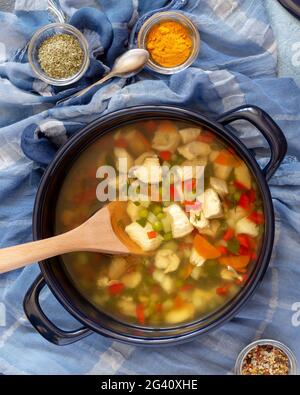 Cuisine nationale juive. Composition verticale des aliments avec grande casserole avec soupe chaude de poulet juif et épices sur fond bleu. Nourriture saine et savoureuse Banque D'Images