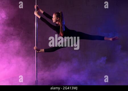 Danseuse de pôle mince en train d'effectuer des fractionnements aériens Banque D'Images