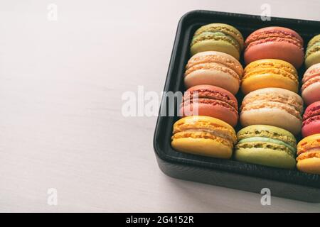 Boîte cadeau macarons assortiment mignon de macaron jaune pastel différentes saveurs - pistache, citron, framboise, vanille Banque D'Images