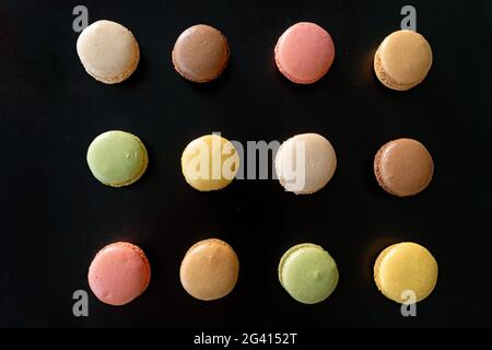 Vue de dessus des macarons sur fond noir. Plaque de cuisson fraîche hors du four sélection de macarons pâtisserie française desserts biscuits Banque D'Images