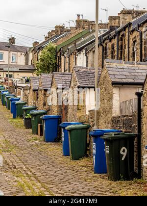 Allée pavée en pente à l'arrière des maisons en terrasse victorienne à Skipton, au Royaume-Uni, avec des lignes de bennes à roulettes Banque D'Images