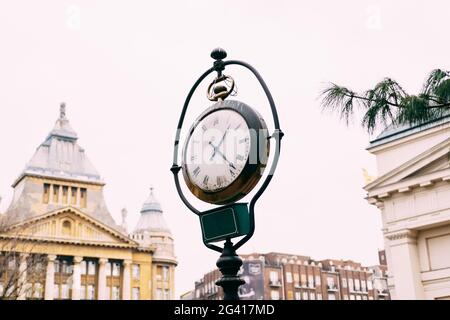 Un ancien poste de rue avec une horloge, dans les rues de Budapest. Banque D'Images