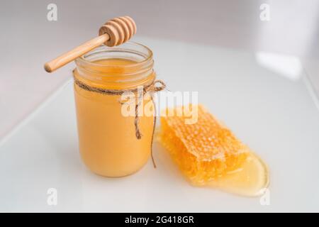 Pot de miel avec un balancier de miel et un nid d'abeille naturel Banque D'Images