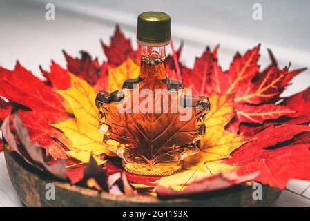 Bouteille de sirop d'érable dans des feuilles d'érable rouge pour un souvenir cadeau touristique. Le Canada classe UN liquide doux ambré provenant de la cabane à sucre du Québec Banque D'Images