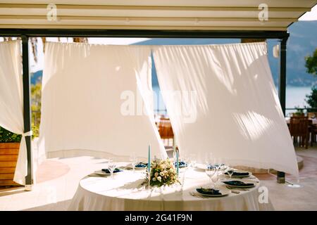 Réception de table de dîner de mariage. Table ronde avec un bouquet de fleurs au centre et des bougies, sur fond blanc Banque D'Images