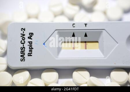 Résultat positif du test RASARS-COV-2 Rapid AG, test positif du virus Covid-19 corona avec comprimés blancs médicaments traitement isolé sur blanc Banque D'Images