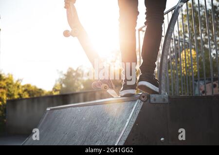 Skater debout sur une rampe dans le parc à roulettes en journée ensoleillée Banque D'Images