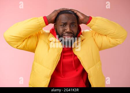 Troublé choqué jeune homme contrarié se sentent mal anxieusement cringing mains tête frowning perdant pari loterie debout s. Banque D'Images