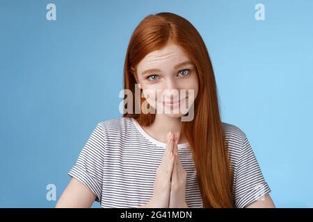 Jolie fille agissant genre ange regarder caméra silly sourire demander s'il vous plaît aider à presser les paumes ensemble prier flirter flirty mendiant favori Banque D'Images