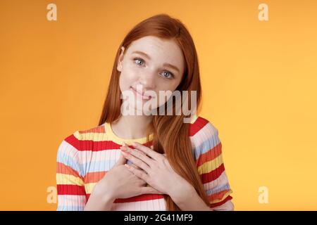 Adorable Silly mignon redhead jeune fille européenne inclinaison tête regarder doucement sourire tendre caméra presse palmiers coeur reconnaissant recevoir Banque D'Images