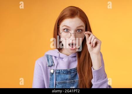 Choc impressionné redhead collègue audition dernière rumeurs intime chute mâchoire regarder plein incrédulité appareil photo confus touch lunettes se Banque D'Images