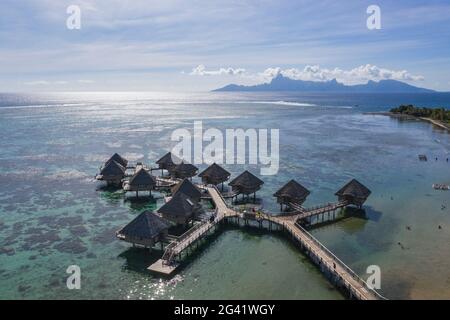 Vue aérienne des bungalows sur l'eau du Tahiti IA ora Beach Resort (géré par Sofitel) avec Moorea Island au loin, près de Papeete, Tahiti, Wi Banque D'Images