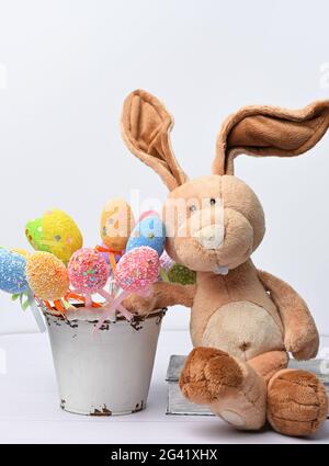 Lapin en peluche sur fond blanc et œufs de pâques colorés décoratifs Banque D'Images